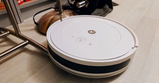 Roomba jumissa vaatetelineen jalkojen päällä