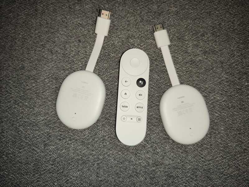 Kaksi Chromecast with Google TV laitetta joiden välissä on valkoinen kaukosäädin