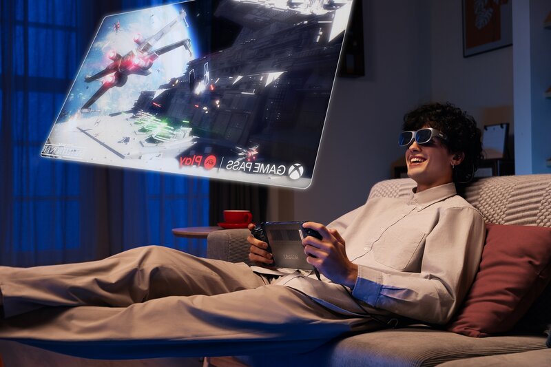 Mies sohvalla Legion Go pelilaite käsissä ja päässä Legion Go lasit. Miehen eteen on hahmoteltu iso virtuaalinen näyttö, jossa näkyy pelisisältöä