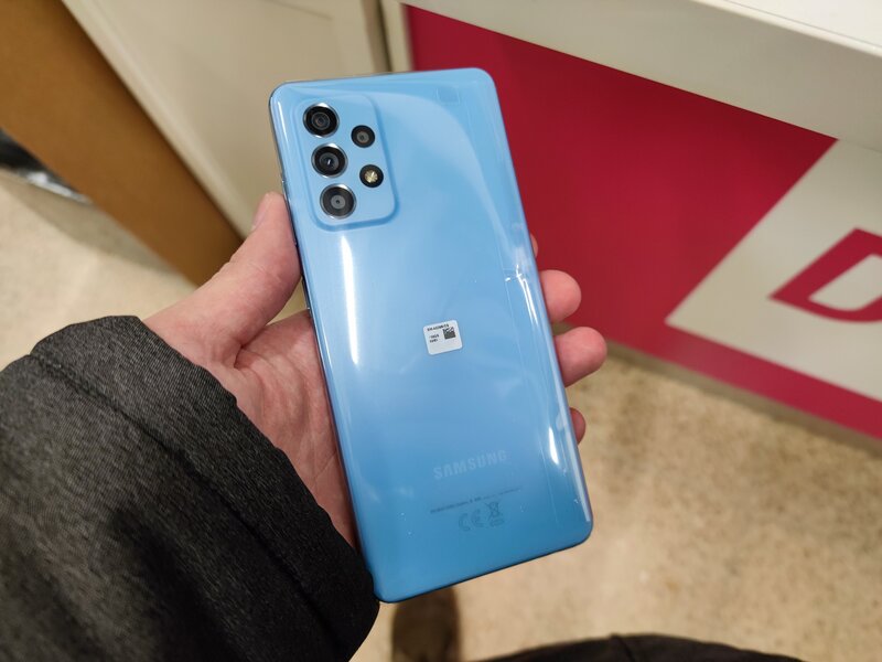 kädessä Galaxy A52 5G puhelinmalli awesome blue värissä